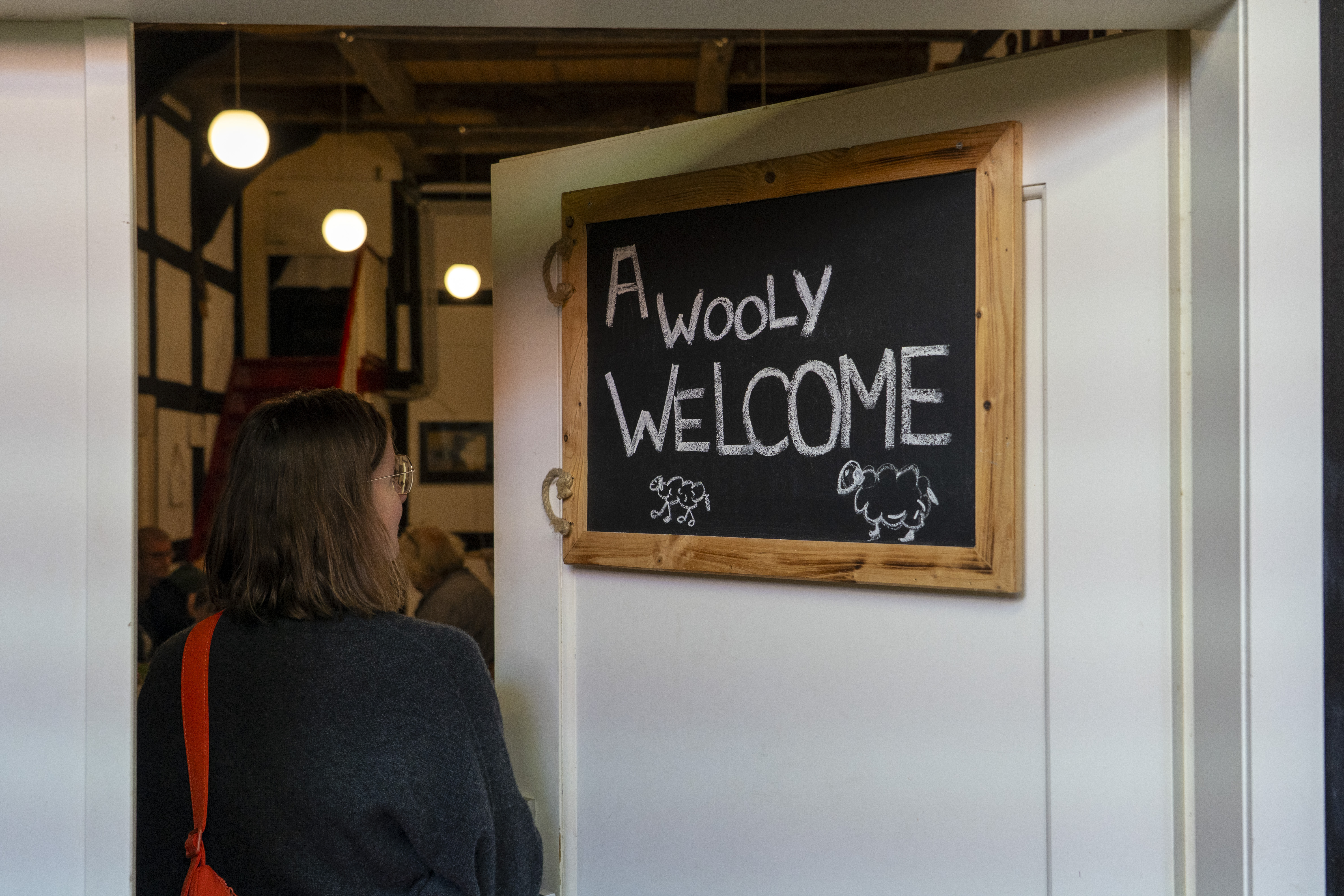 A women next to the sign "A wooly welcome"